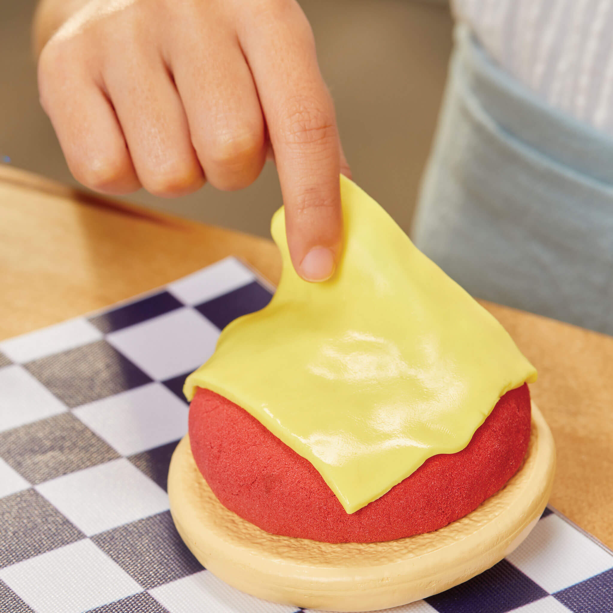 Play hamburger with yellow cheese on a checkered tablecloth