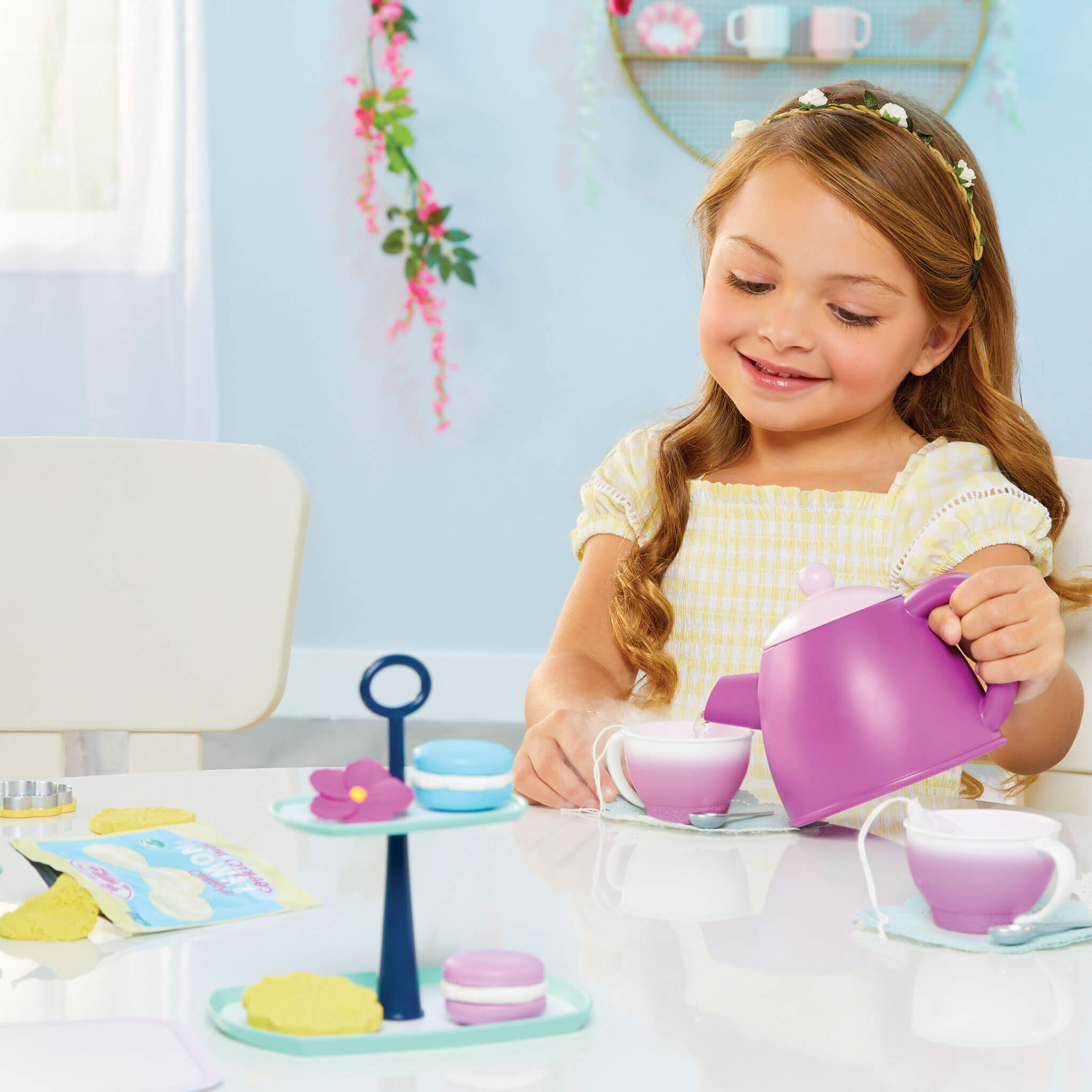 Young girl playing with a toy tea set 